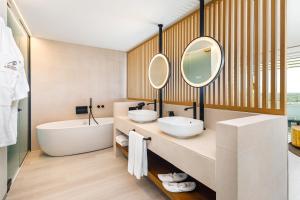 a bathroom with two sinks and a tub and mirror at AP Eva Senses in Faro