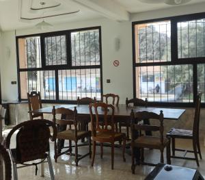 uma sala de jantar com mesa, cadeiras e janelas em TAZEKKA PARC HOTEL em Taza