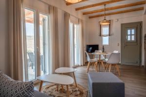 uma sala de estar com um sofá, uma mesa e cadeiras em Epithea Suites Kythnos 3 με ιδιωτική πισίνα em Kythnos