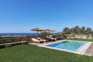 una piscina con due sedie e un ombrellone di Alba Lilia Cretan Villas a Pitsidia