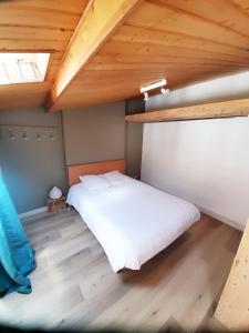 ラ・ロシェルにあるL'Atelierの白いベッドと木製の天井が備わるベッドルーム1室が備わります。