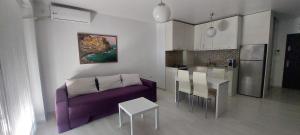 sala de estar con sofá púrpura y cocina en Apartament Ariadna Residence, en Constanţa