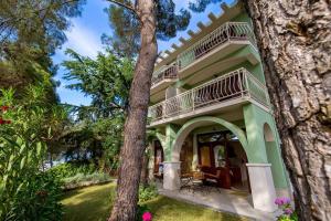 a green house with a balcony and trees at House Dinka with Pool in Porat