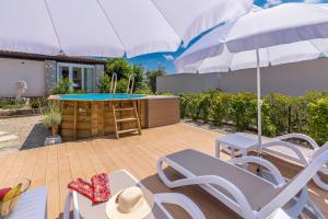 a patio with a table and chairs and an umbrella at Kuća za odmor Villa Seahorse in Pinezici