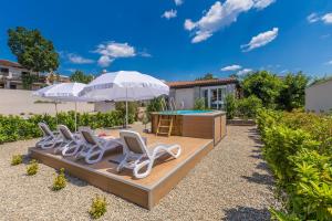 a row of chairs and a pool with an umbrella at Kuća za odmor Villa Seahorse in Pinezici