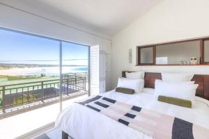 a bedroom with a large bed and a large window at Awesome Views & Beach Proximity in Cape St Francis