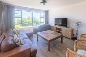 a living room with a couch and a tv at Awesome Views & Beach Proximity in Cape St Francis