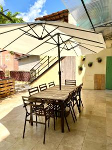 Appartement terrasse vue lac في بريل-سور-رويا: طاولة خشبية مع كراسي ومظلة على الفناء