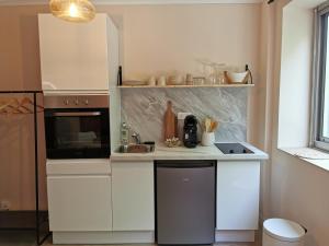 una cocina con armarios blancos y fregadero en Studio confort - clim - ascenseur, en Cavaillon