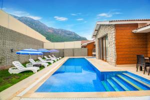 a swimming pool with chairs and umbrellas next to a building at Patara Titanic 3+1 Villa, Özel Havuzlu, Fethiye in Fethiye