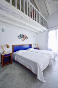 a white bedroom with two beds and two lamps at Kalidon beach Hotel in Kokkari