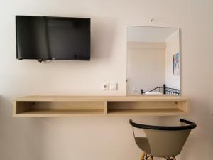 a flat screen tv on a wall with a chair at Vironas Hotel in Himare +37 photos