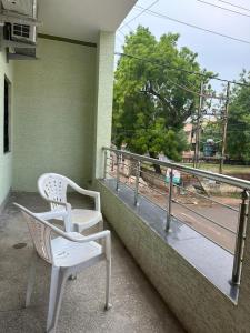 un par de sillas blancas sentadas en un balcón en SunRays - Unique 3BHK in the Heart of the City en Gwalior