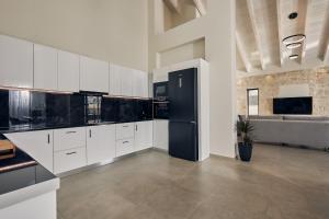 a kitchen with white cabinets and a black refrigerator at Mouzaki's Stone Villas in Volímai