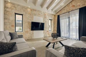 uma sala de estar com uma parede de pedra e uma televisão em Mouzaki's Stone Villas em Volímai