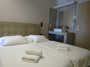 a bedroom with a large white bed with two towels on it at Beach Hotel Božikovina in Podstrana