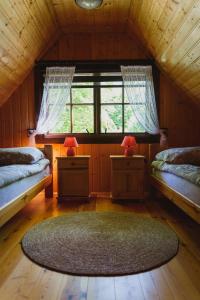 a attic room with two beds and a large rug at Nad Lipcykiem in Nowy Gaj