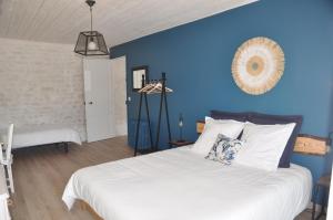 um quarto com uma grande cama branca e uma parede azul em Le Hangar em Saint-Jean-dʼAngély