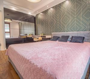 a bedroom with a large pink bed and a tub at Szmaragdowy Spichlerz Apartament in Gdańsk