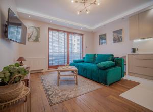 a living room with a green couch and a kitchen at Szmaragdowy Spichlerz Apartament in Gdańsk