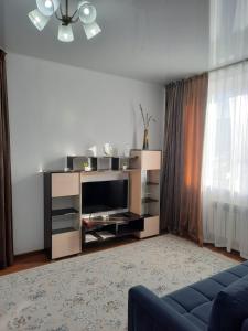 sala de estar con TV y sofá azul en Апарт отель Welcome, en Taldykorgan