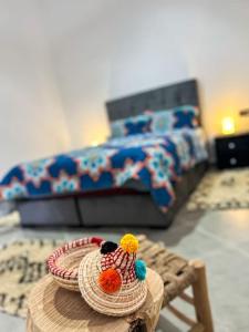 ein Schlafzimmer mit einem Bett und einem Tisch mit einem Hut in der Unterkunft Oasis Villa Essaouira in Essaouira