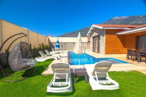 ein Pool mit einem Haufen Stühle und einem Tisch in der Unterkunft Tlos Yalı 3+1 Villa, Özel Havuzlu, Fethiye in Fethiye