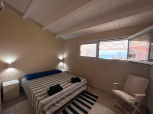 - une chambre avec un lit, une chaise et une fenêtre dans l'établissement Fronte Mare S'Arena Scoada, à Putzu Idu