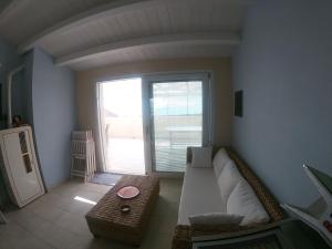 - un salon avec un canapé et une grande fenêtre dans l'établissement Fronte Mare S'Arena Scoada, à Putzu Idu