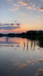 une personne sur une planche de paddle sur un lac au coucher du soleil dans l'établissement Słonecznikowe gniazdko, à Miłomłyn