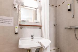 La salle de bains est pourvue d'un lavabo, d'un miroir et d'une douche. dans l'établissement Hôtel VAL FLORES LOGIS, à Biarritz