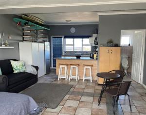 a living room and kitchen with a couch and a table at Casual, beachy and 100m to Seals Surf Spot in Cape St Francis