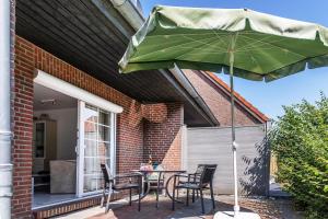 a patio with a table and chairs and an umbrella at Ferienhaus 50009 in Carolinensiel