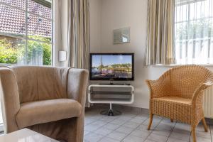 uma sala de estar com uma televisão e uma cadeira em Ferienhaus 50009 em Carolinensiel
