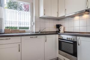 uma cozinha com armários brancos, um fogão e uma janela em Ferienhaus 50009 em Carolinensiel