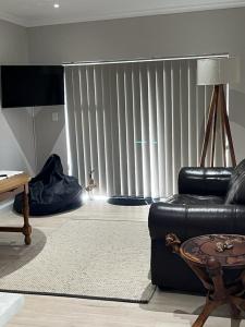 sala de estar con sofá de cuero negro y mesa en Metanoia Kingswood Golf Estate, en George