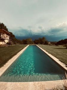 a swimming pool with blue water in a field at Maison Drôles d'Oiseaux in Plieux