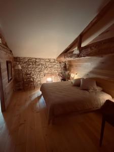 - une chambre avec un lit et un mur en pierre dans l'établissement Maison Drôles d'Oiseaux, à Plieux