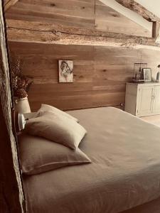 Ce lit se trouve dans une chambre dotée d'un mur en bois. dans l'établissement Maison Drôles d'Oiseaux, à Plieux