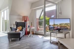 a living room with a tv and a chair at 50171 Haus Antje I in Harlesiel