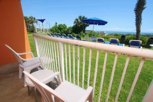 uma varanda com cadeiras e mesas e um guarda-sol em Bar Harbor em Myrtle Beach