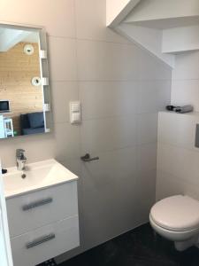 ein Badezimmer mit einem weißen Waschbecken und einem WC in der Unterkunft Domki Wypoczynkowe "Sea Breeze" in Rewal