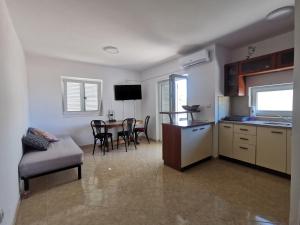 a kitchen and living room with a table and chairs at Apartmani Lešić Tribunj in Tribunj