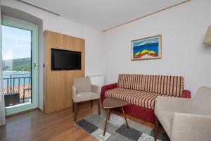 a living room with a couch and a tv and a window at Hotel Nostromo in Rabac