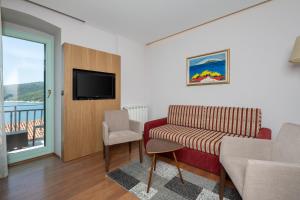 sala de estar con sofá, TV y ventana en Hotel Nostromo, en Rabac