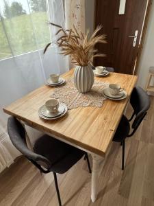 einem Holztisch mit zwei Stühlen und einer Vase darauf in der Unterkunft Wagończyk in Grzegrzółki