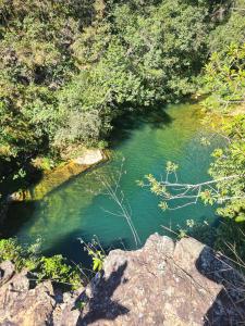 un río con agua verde, árboles y rocas en Pousada Mirante do Cerrado, en Delfinópolis