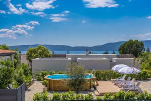 a backyard with a pool and chairs and an umbrella at Kuća za odmor Villa Seahorse in Pinezici