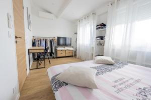 een witte slaapkamer met een bed met kussens en een bureau bij Duplex avec extérieur, 30 min de Paris et Disney in Saint-Maur-des-Fossés
