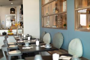 a dining room with tables and chairs and windows at Hôtel de la Baie in Crozon